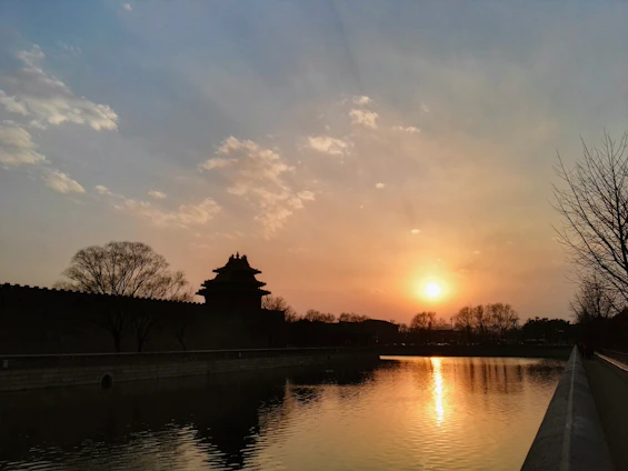 A serene image of a traditional Eastern temple silhouette blending into a modern Western city skyline at sunset.