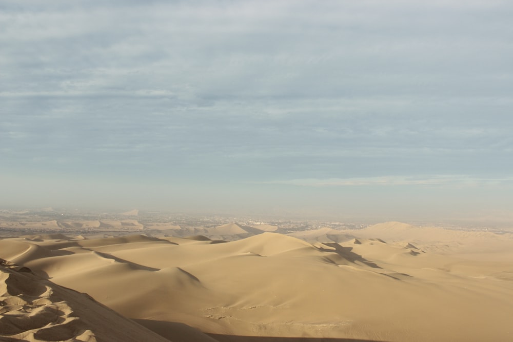 brown sand under white clouds during daytime