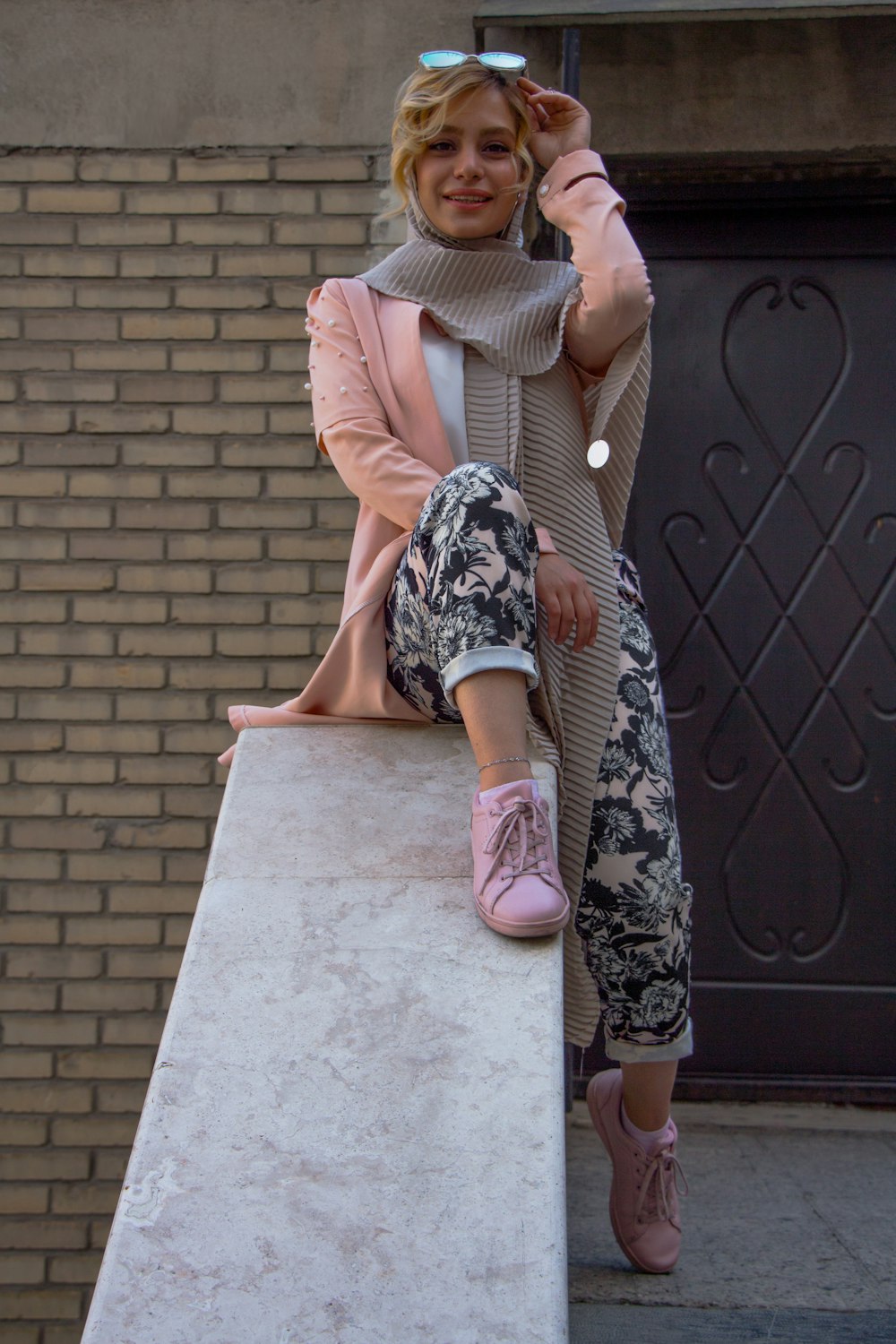 woman in brown and black floral dress sitting on gray concrete bench