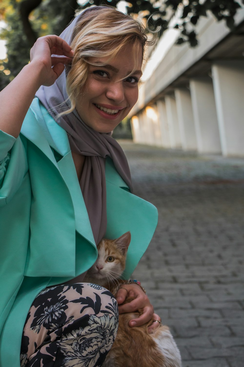 woman in green coat holding brown tabby kitten