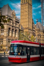 red and white tram in front of brown concrete building during daytime