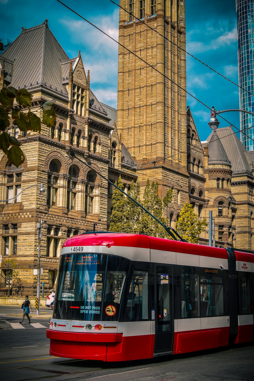 red and white tram in front of brown concrete building during daytime