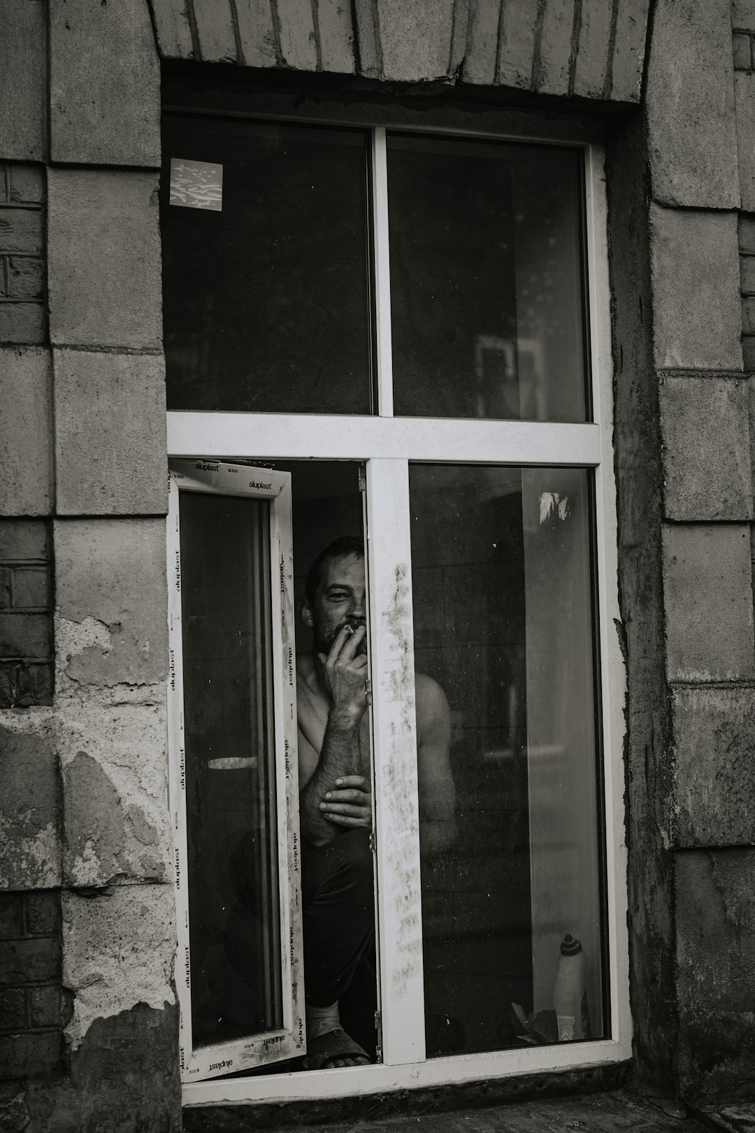 man in gray coat standing beside glass window