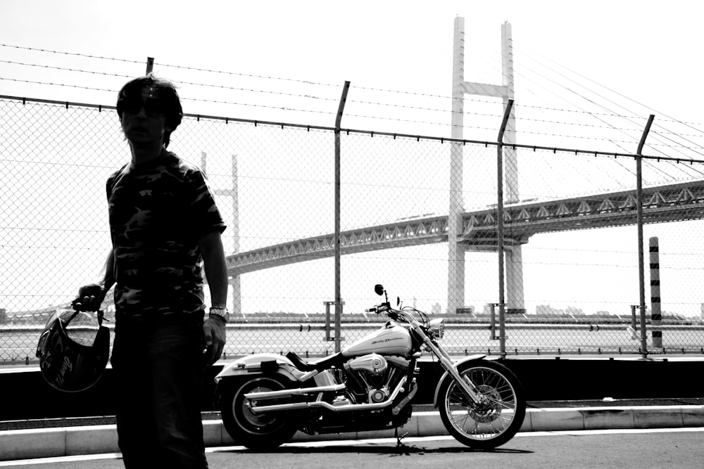 Hombre con chaqueta negra y jeans de mezclilla azules de pie junto a motocicleta negra