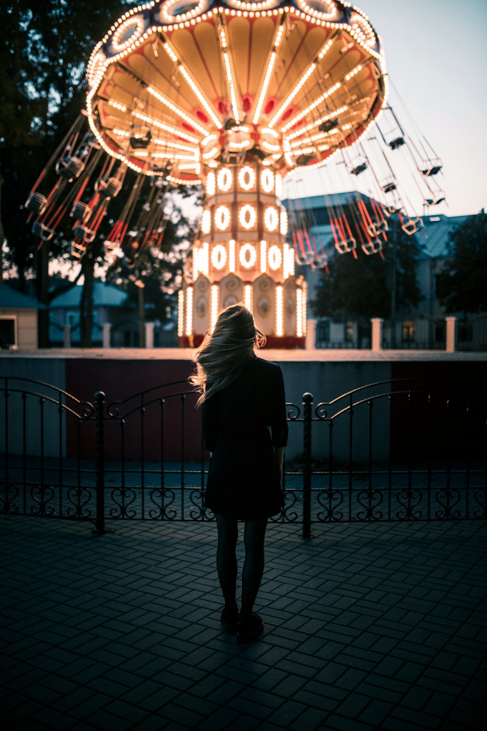 woman in black coat standing in front of lighted building