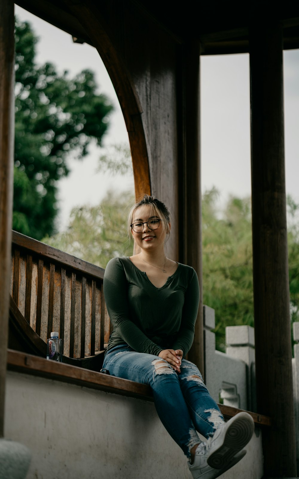 woman in black long sleeve shirt and blue denim jeans sitting on brown wooden bench during