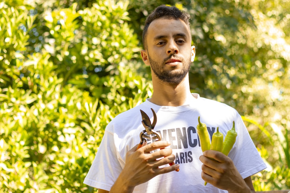 man in white crew neck t-shirt standing near green leaf tree during daytime