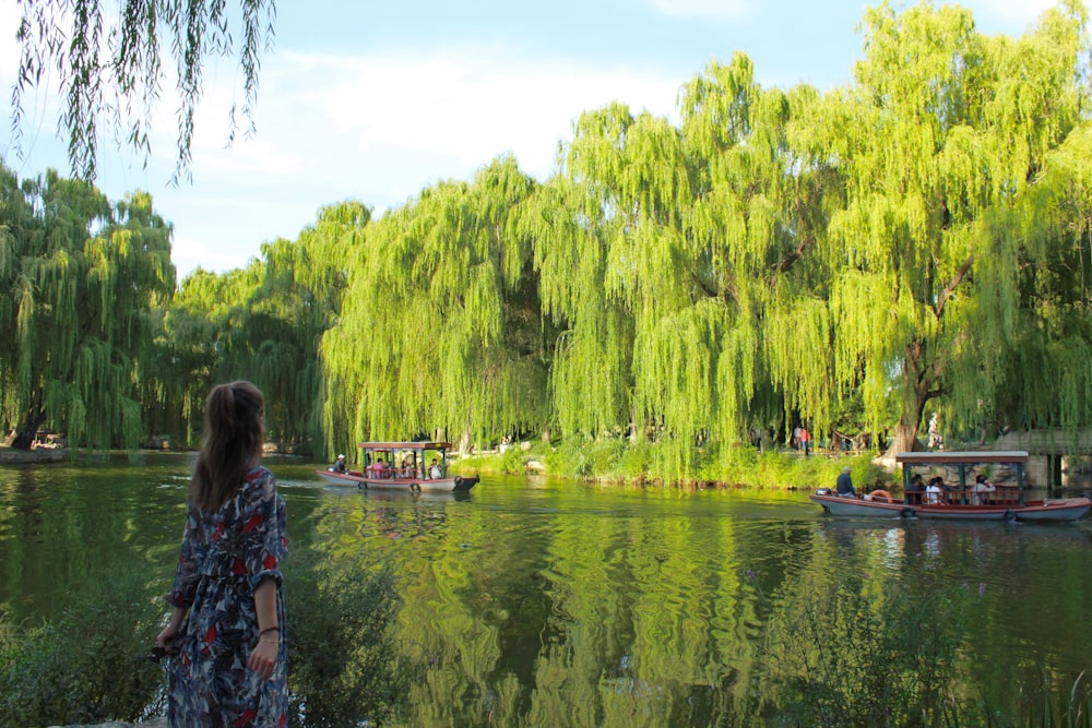 woman in blue and pink floral dress standing on boat on lake during daytime