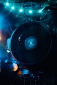 A close-up view of a computer cooling fan with LED lights illuminating the scene in blue. The fan, marked with 'AMD', spins, creating a dynamic blur in the center. Surrounding components are partially visible under the bluish glow, adding a futuristic and high-tech feel to the composition.