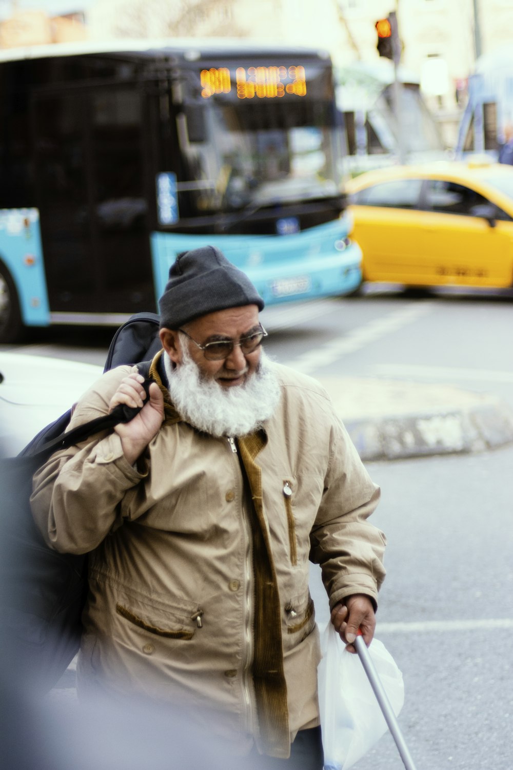 man in brown jacket and blue knit cap standing on sidewalk during daytime