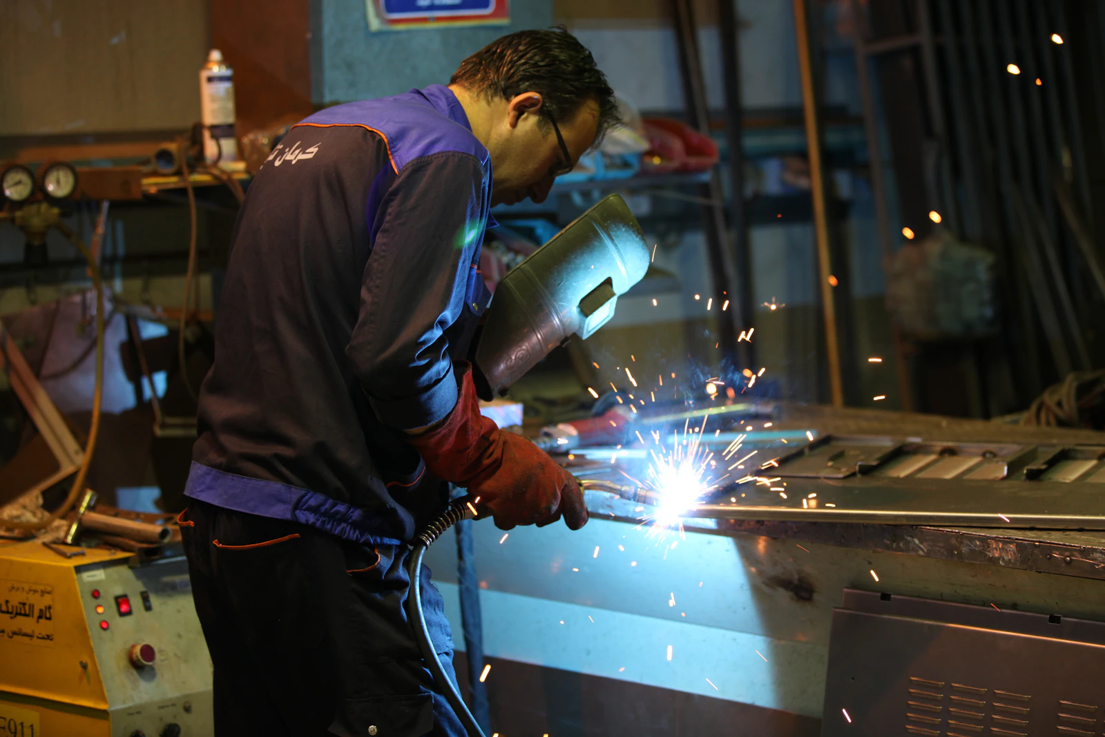Soudeur équipé travaillant sur une pièce métallique en atelier