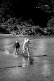 Cinematic image of children running joyfully on a sandy beach with charcoal shadows.