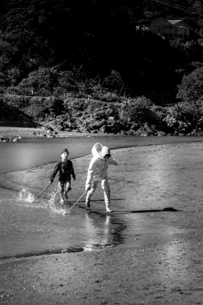 Cinematic image of children running joyfully on a sandy beach with charcoal shadows.