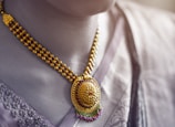 Close-up of an elegant gold necklace with intricate Arabic designs.