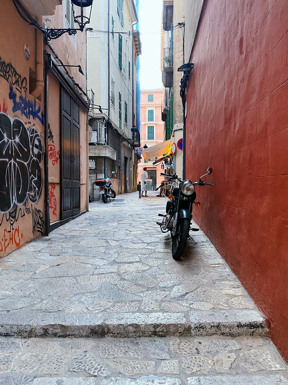 black motorcycle parked beside brown concrete building during daytime