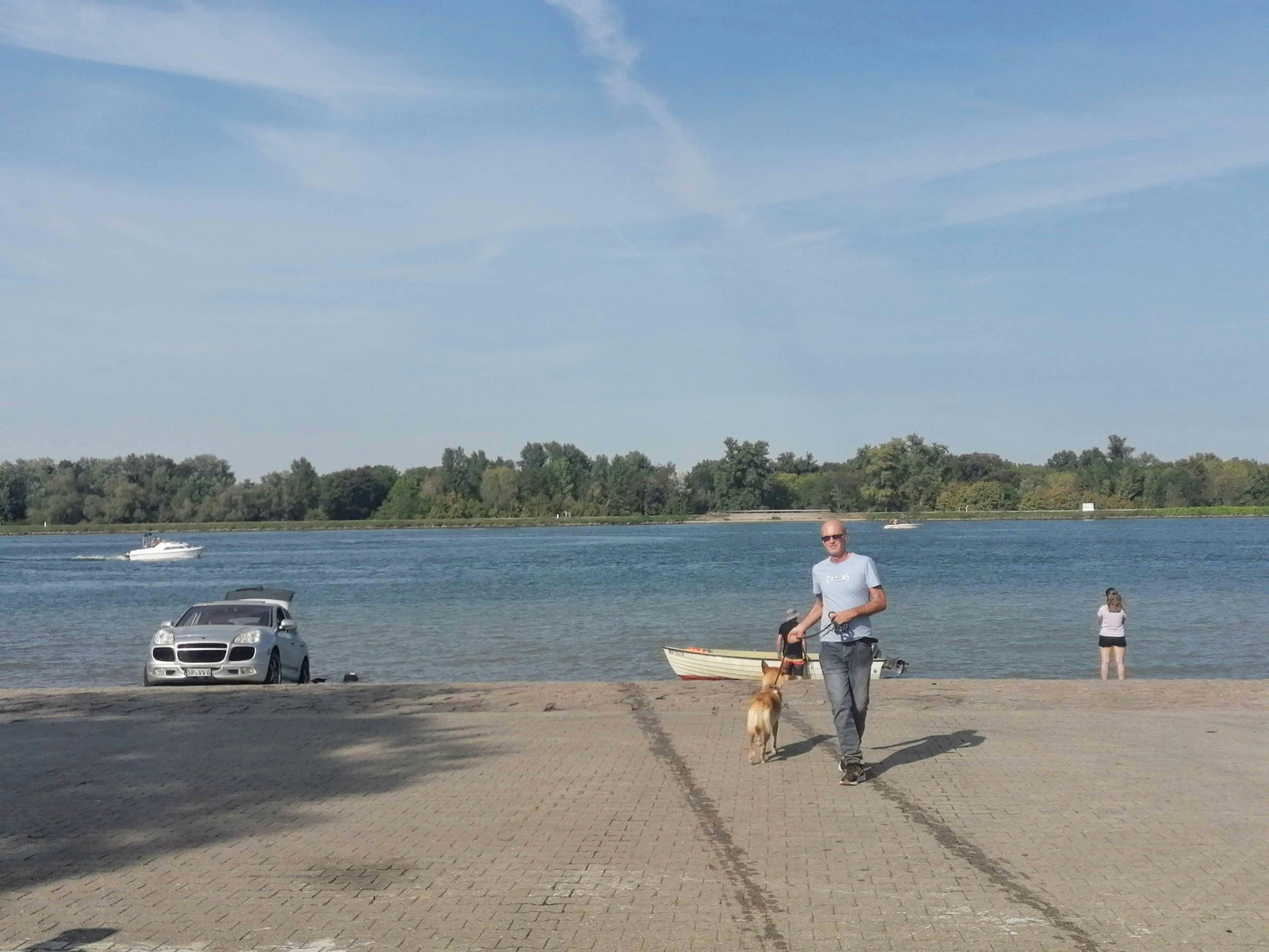 man in white shirt and blue denim jeans riding bicycle on gray concrete road during daytime