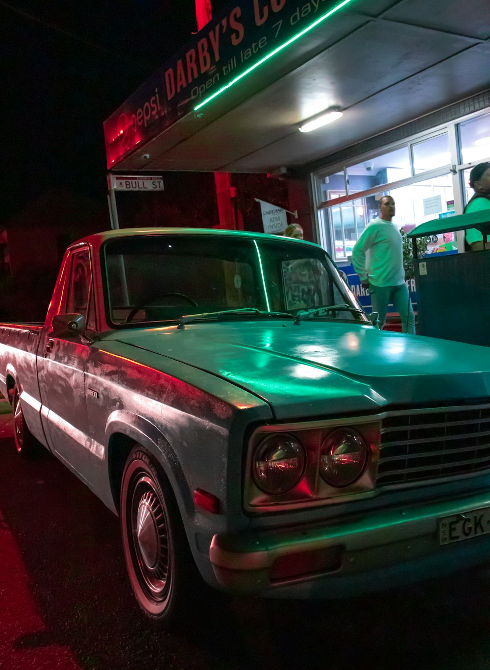 green classic car parked in front of store