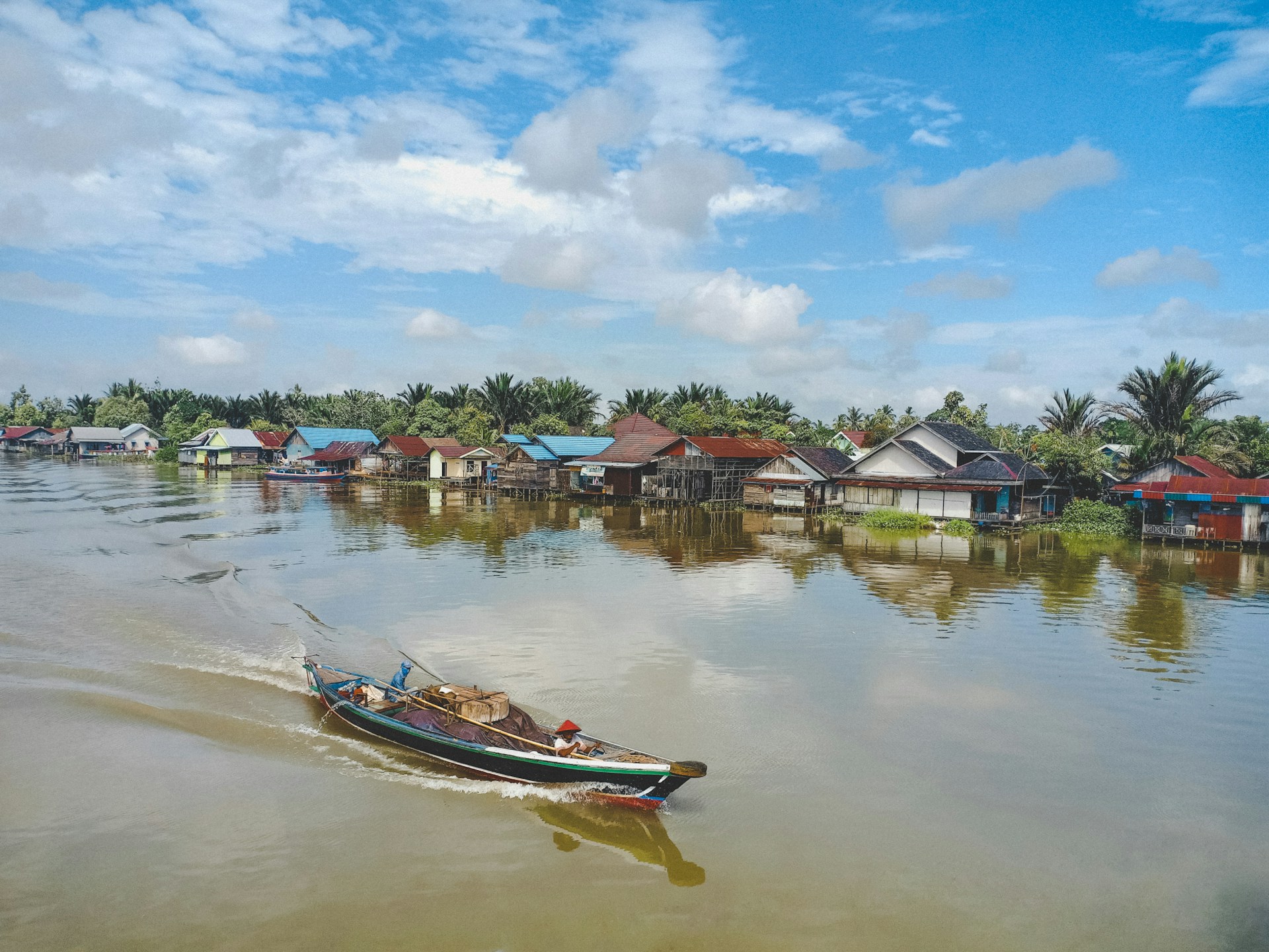 white and red boat on water near houses under blue sky during daytime