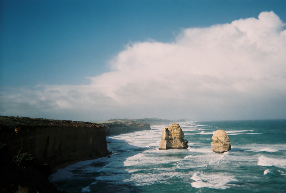 brown rock formation on sea under blue sky during daytime