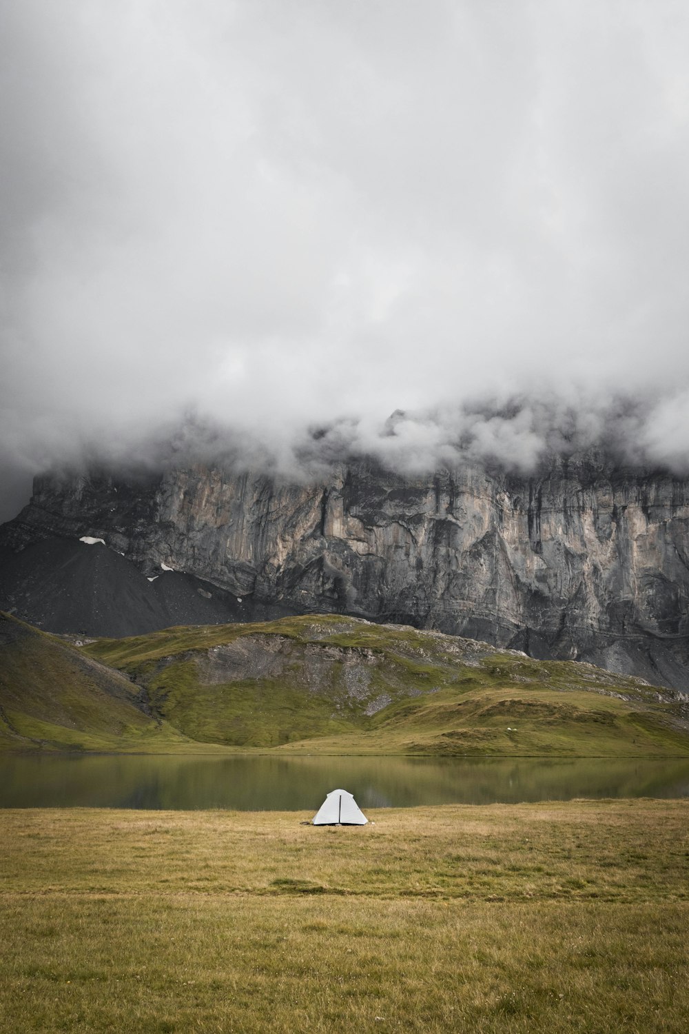 white tent on green grass field near gray rocky mountain during daytime