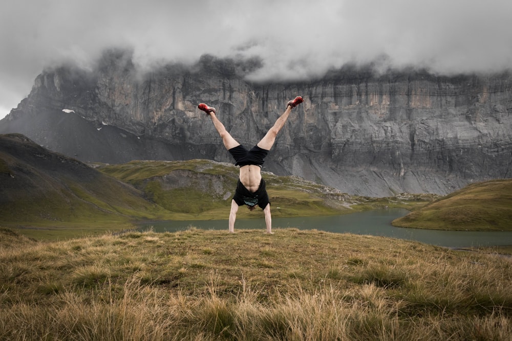 woman in black sports bra and black shorts doing yoga on green grass field during daytime