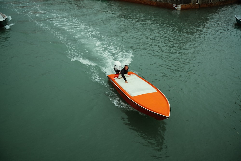 person riding on red and white kayak on body of water during daytime