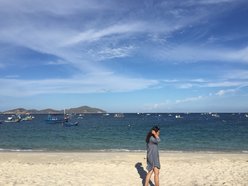 donna in camicia nera in piedi sulla spiaggia di sabbia bianca durante il giorno