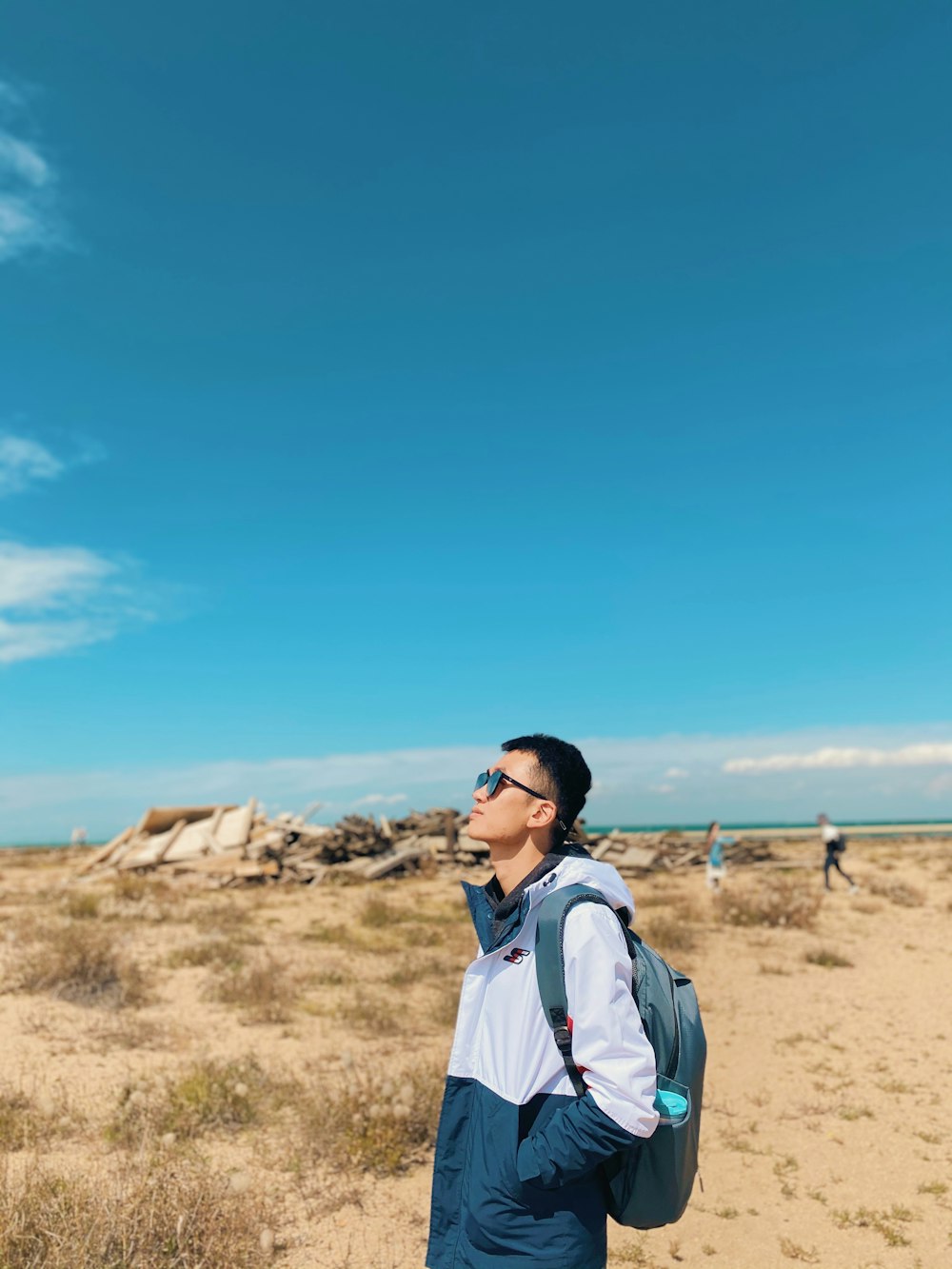 man in white jacket standing on brown sand during daytime