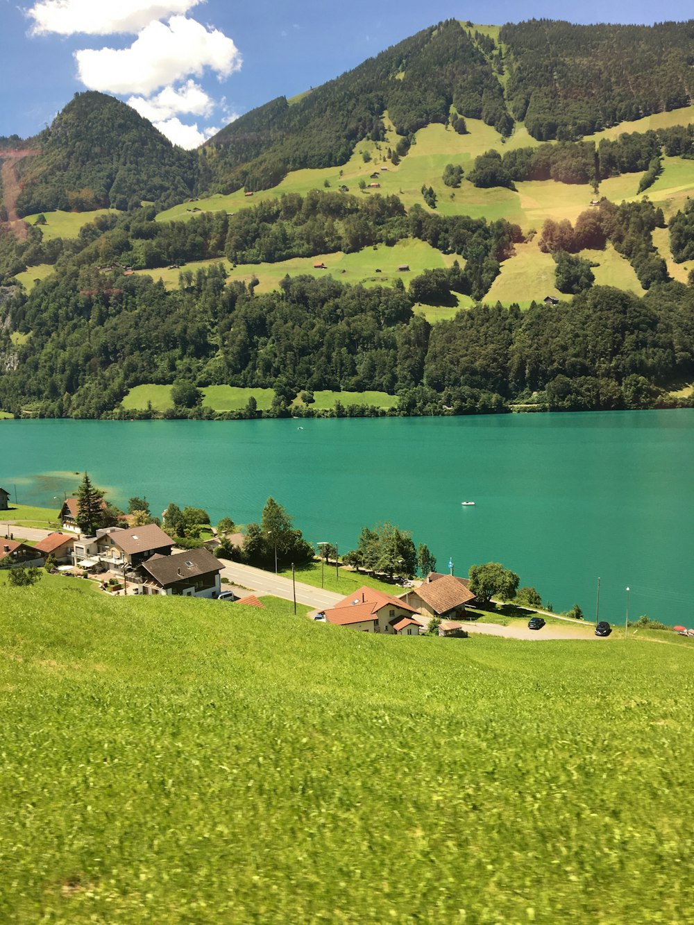 houses near lake and green mountains during daytime