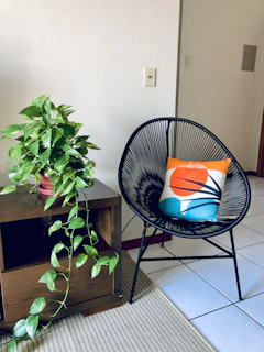 Cozy reading nook with a plush chair, natural fiber rug, and a small black side table holding a plant