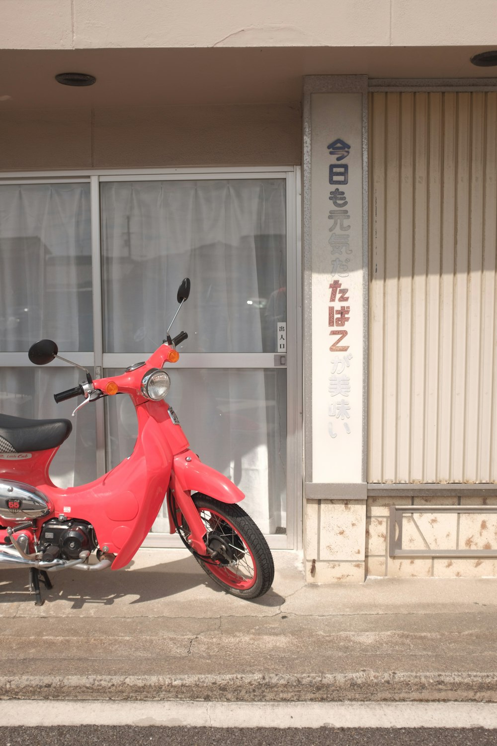 red and black motorcycle parked beside white building