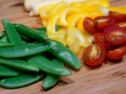 Close-up of fresh vegetables and herbs arranged on a wooden cutting board.