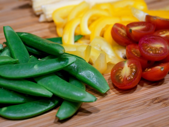 A close-up of a sleek kitchen knife slicing through fresh vegetables on a wooden cutting board.