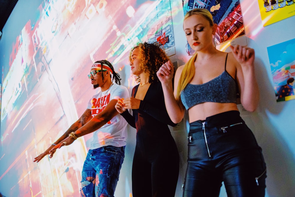 2 women in black tank top and blue denim jeans standing beside wall with graffiti