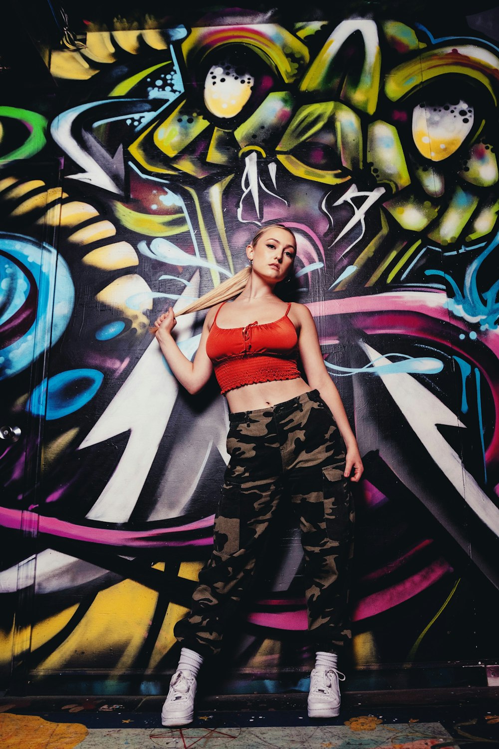 woman in red sports bra and black and white pants standing beside graffiti wall
