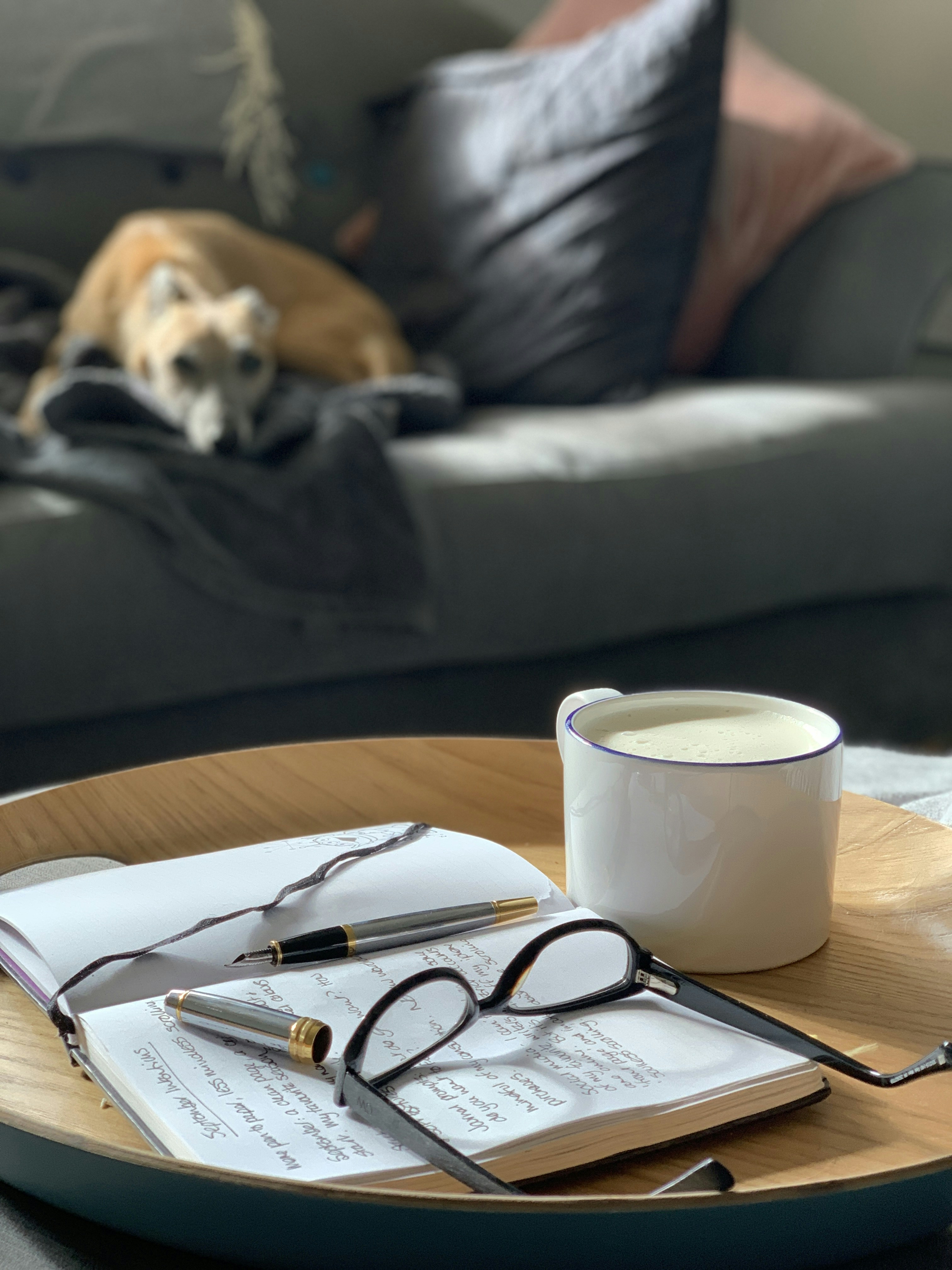 A person writing in a journal with a cup of coffee.