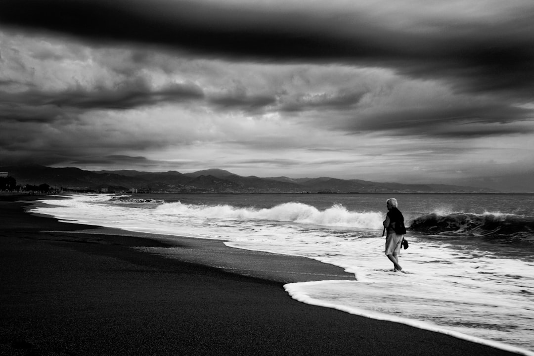 grayscale photo of couple walking on beach