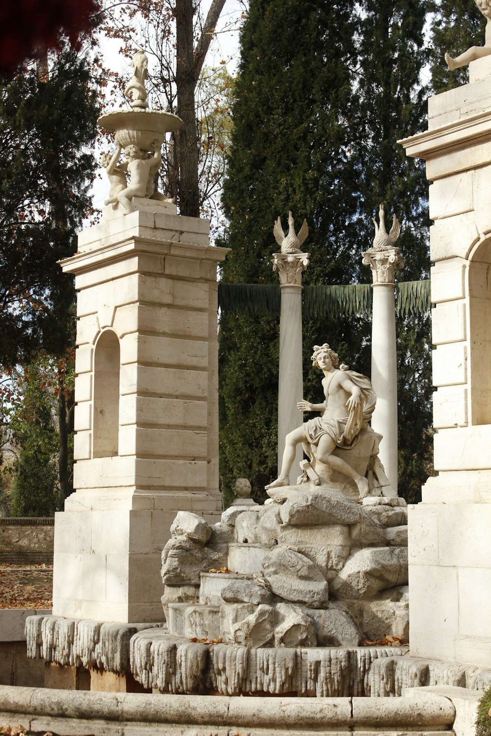 white concrete statue near green trees during daytime