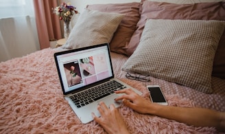 person using macbook pro on bed