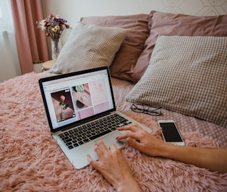 person using macbook pro on bed