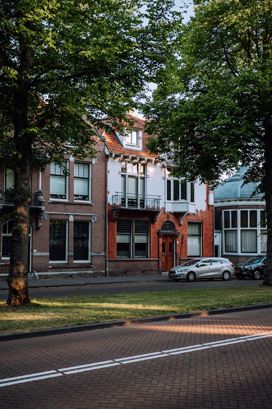 white sedan parked beside brown and white concrete building during daytime in Haarlem Netherlands