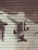 A metal roller shutter with peeling paint and faded red characters painted across it. The surface shows signs of wear and aging, giving a rustic appearance.