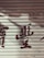 A metal roller shutter with peeling paint and faded red characters painted across it. The surface shows signs of wear and aging, giving a rustic appearance.