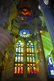 Majestic stained glass window illuminating a serene church interior with warm burgundy and gold tones.