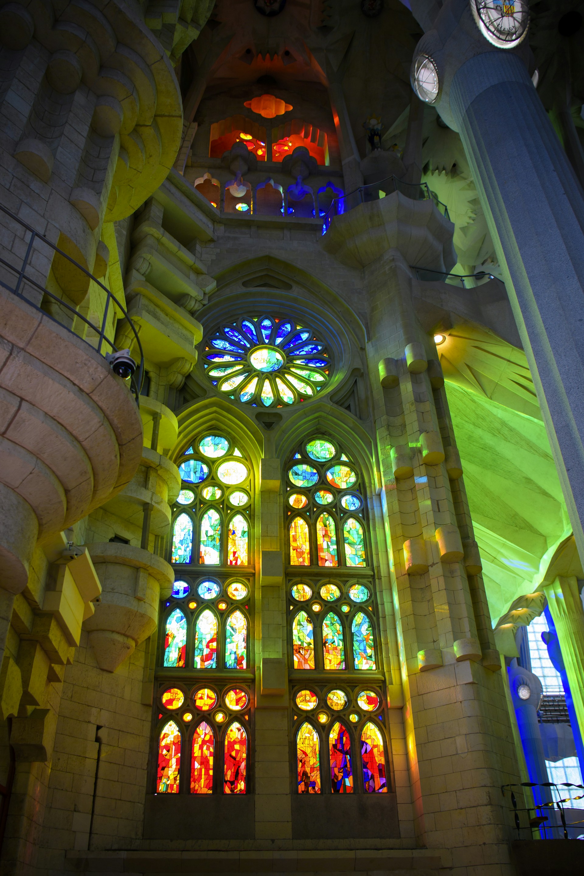 A vibrant stained glass window depicting a saint, casting colorful light onto the wooden pews of a historic church.