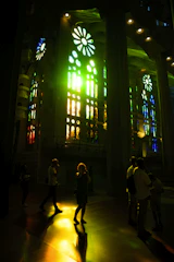 A diverse group of people gathered in worship, bathed in warm sunlight streaming through stained glass windows.