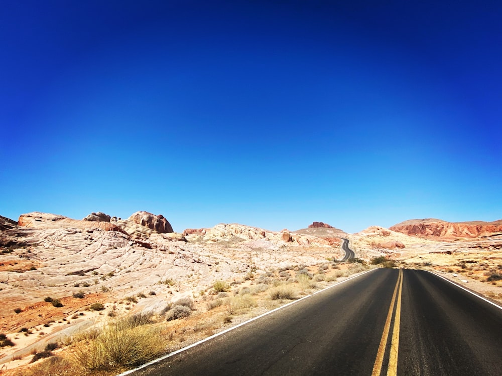 gray asphalt road between brown grass field during daytime