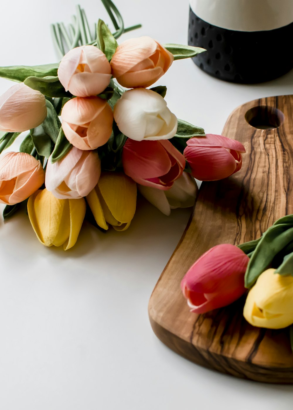 yellow and red tulips on brown wooden chopping board