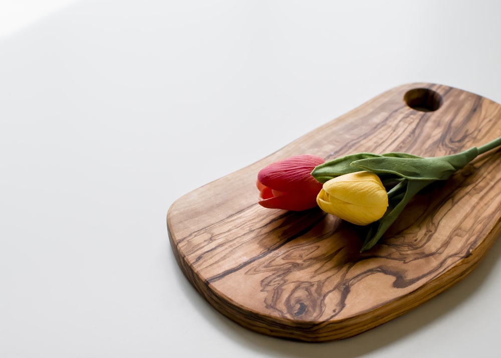 red and yellow flower on brown wooden chopping board