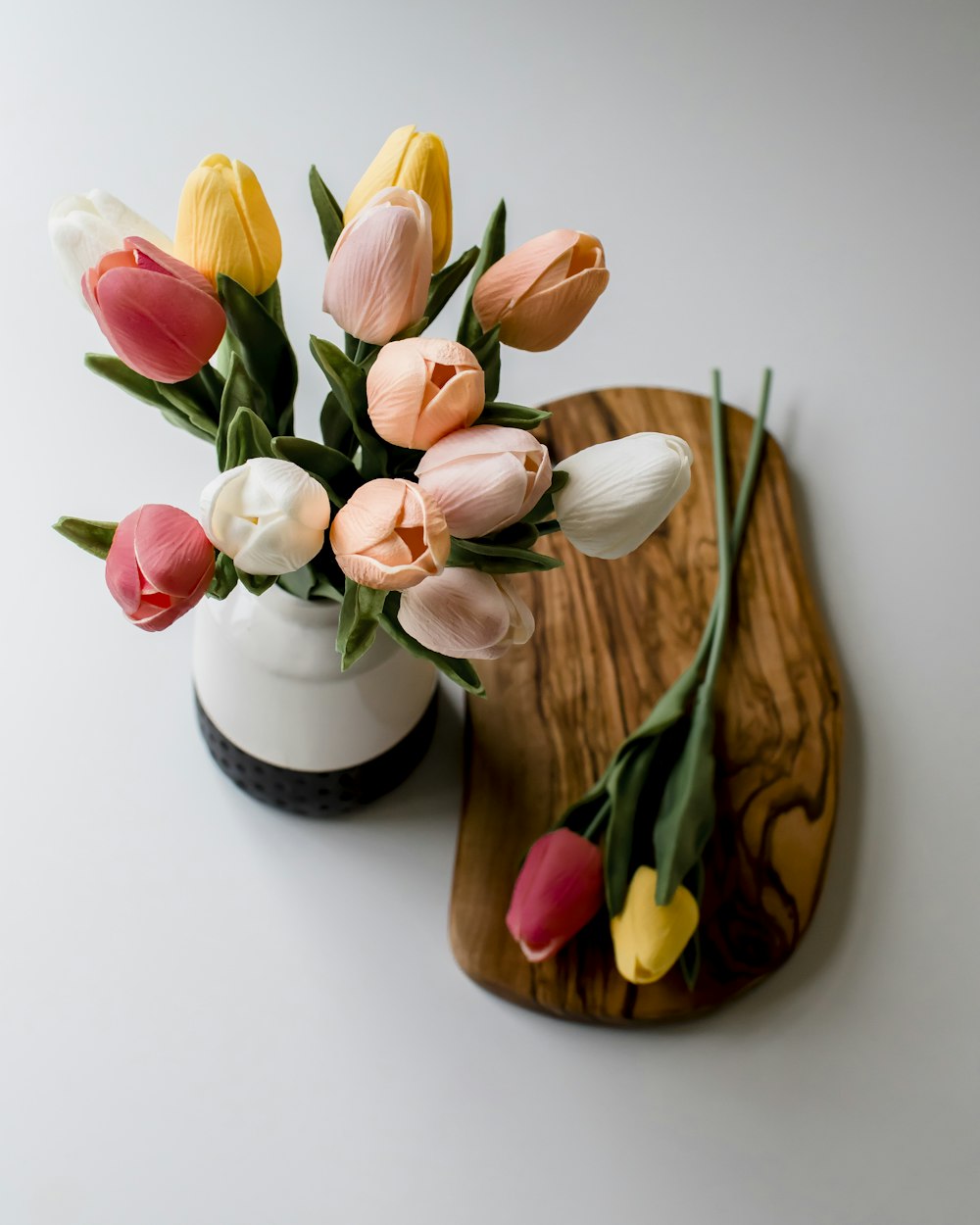 tulipas rosa e branca em vaso de cerâmica branco e marrom